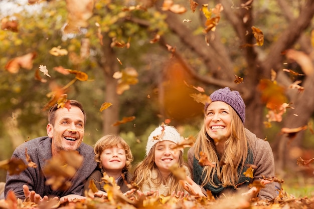 Sonriente joven familia arrojando hojas alrededor