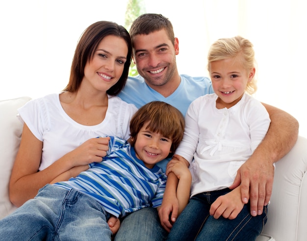 Sonriente joven familia sentada en el sofá