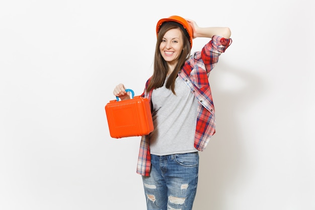 Sonriente joven hermosa mujer en ropa casual casco protector con estuche con instrumentos o caja de herramientas aislado sobre fondo blanco. Instrumentos, herramientas para sala de renovación. Reparar el concepto de hogar.