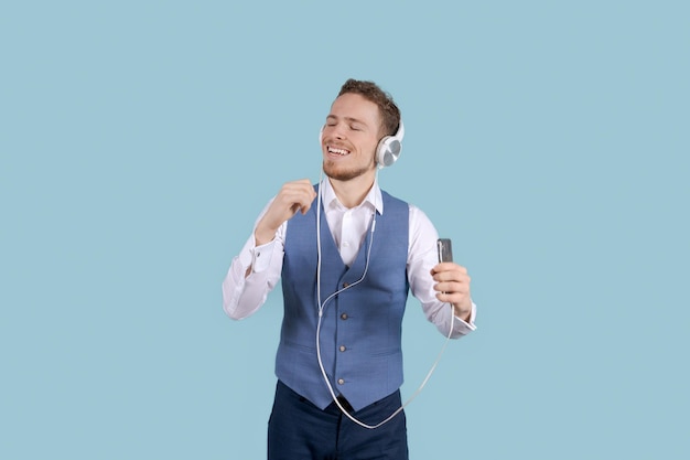 Sonriente joven hombre de negocios con camisa blanca con auriculares escuchando música