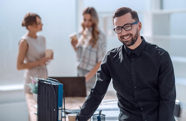 Sonriente joven hombre de negocios de pie en la oficina