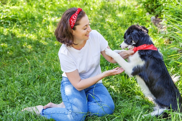 Sonriente joven jugando con cachorro de perro border collie al aire libre