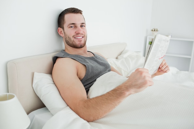 Sonriente joven leyendo un periódico