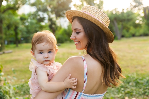 Sonriente joven madre con su pequeña hija en el parque