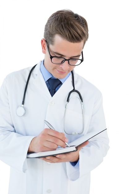 Sonriente joven médico escribiendo en el cuaderno