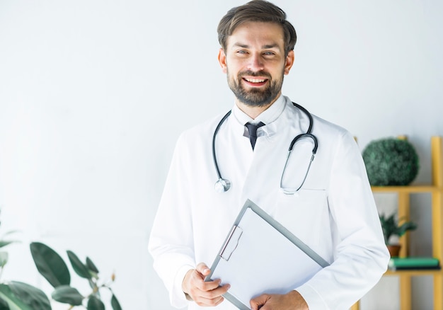 Sonriente joven médico con portapapeles