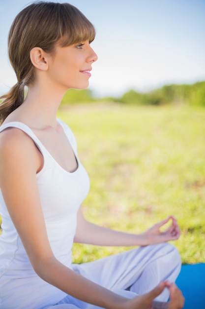 Sonriente joven meditando en posición de loto