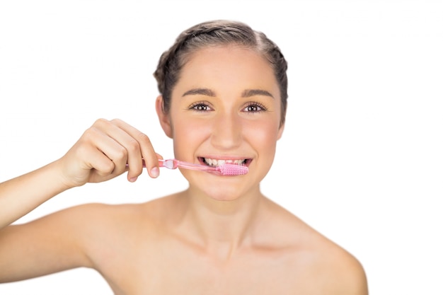 Sonriente joven modelo cepillándose los dientes