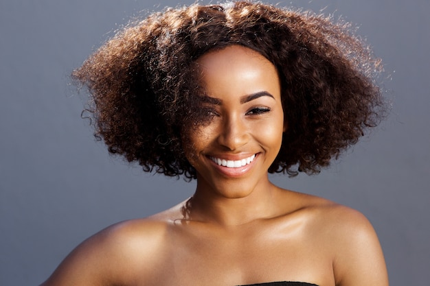 Sonriente joven modelo de moda africana con pelo rizado