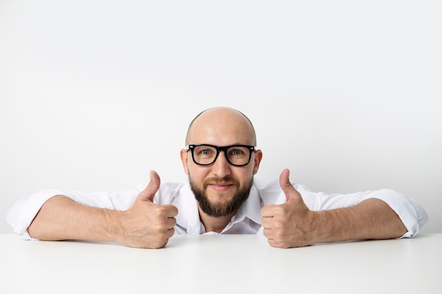 Sonriente joven mostrando Thumbs up gesto de clase sobre fondo blanco.