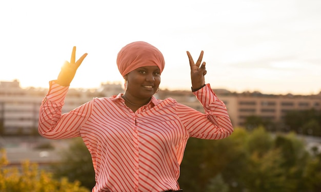 Sonriente joven mujer afro haciendo un gesto de paz