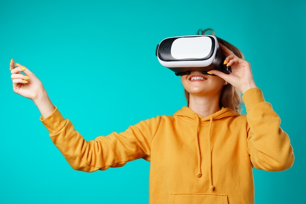 Sonriente joven mujer casual con gafas VR contra azul