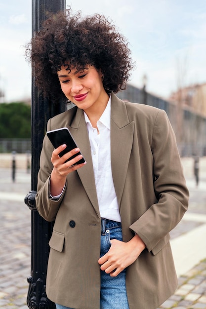 Sonriente joven mujer latina revisando su teléfono