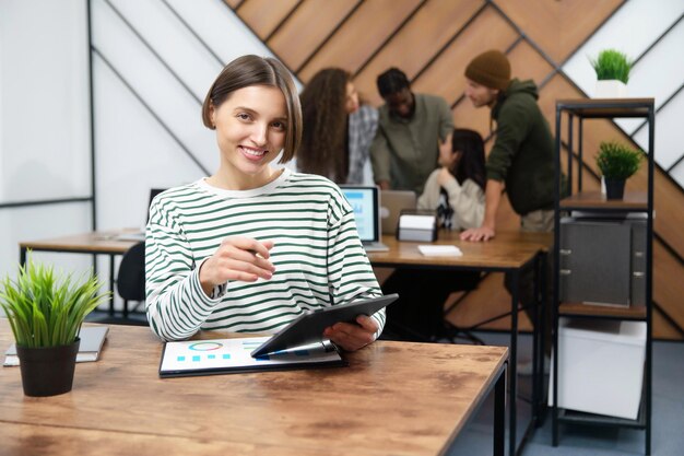 Sonriente joven mujer de negocios sentada en su escritorio