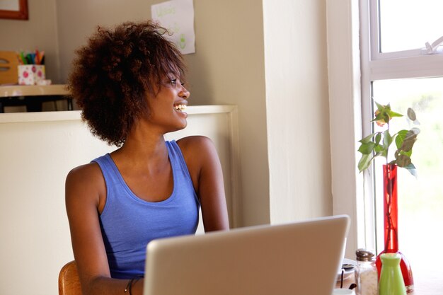 Foto sonriente joven mujer negra usando la computadora portátil en el café