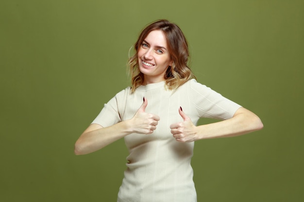 Sonriente joven mujer satisfecha mostrando los pulgares para arriba como recomendar servicio sobre fondo verde bueno