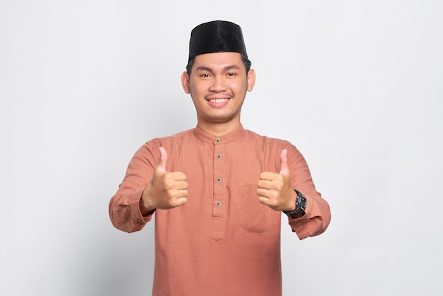Sonriente joven musulmán asiático mostrando Thumbs up gesto aislado sobre fondo blanco.