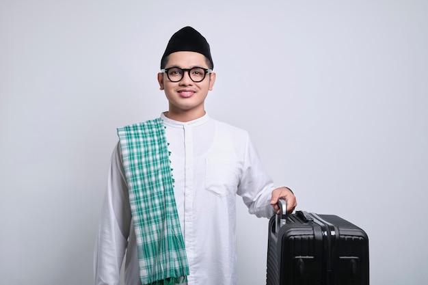 Foto sonriente joven musulmán asiático sosteniendo una maleta negra lista para la festividad eid mubarak