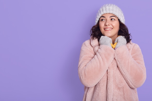 Sonriente joven muy alegre vistiendo gorra y abrigo de piel caliente