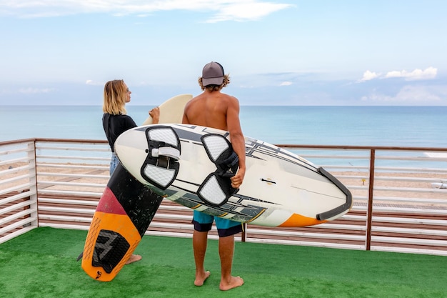 Sonriente joven pareja activa surfistas relajándose en la playa después del deporte con tabla de surf Estilo de vida saludable Deportes acuáticos extremos