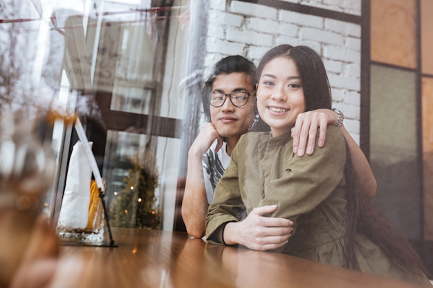 Sonriente joven pareja amorosa asiática en el café