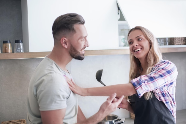 Sonriente joven pareja cocinando comida en la cocina