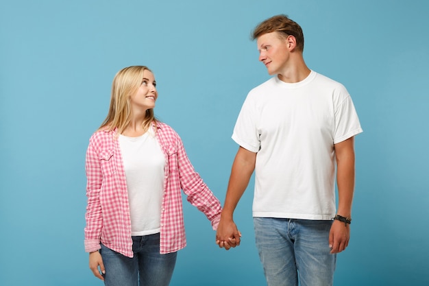 Sonriente joven pareja dos amigos chico y mujer en blanco rosa camisetas en blanco vacías posando