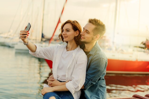 Foto sonriente joven pareja de enamorados hace retrato selfie con teléfono. concepto romántico