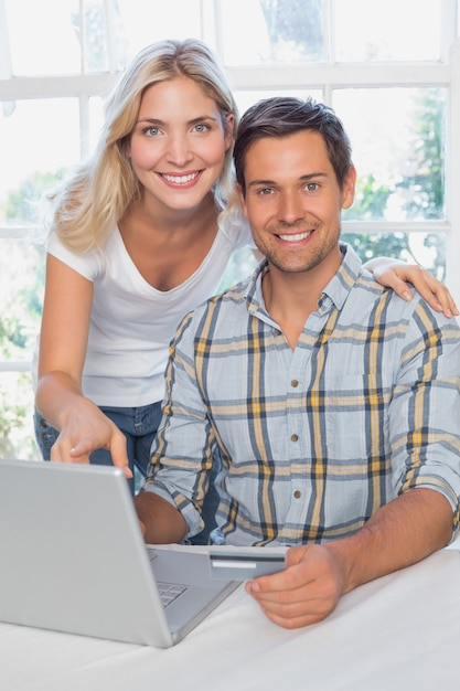 Sonriente joven pareja haciendo compras en línea en casa