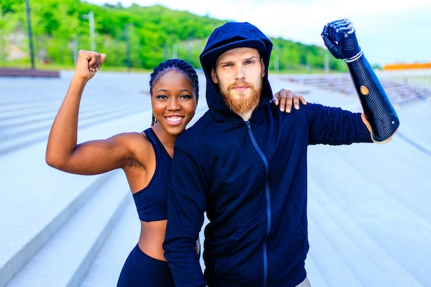 Sonriente joven pareja de raza mixta en ropa deportiva calentando al aire libre fondo sity temprano en la mañana