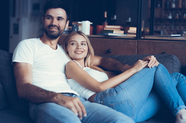 Sonriente joven pareja relajarse y ver la televisión en casa