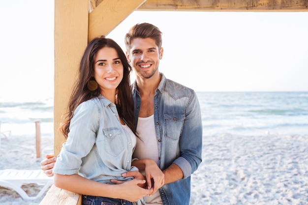 Sonriente joven pareja romántica en el amor de pie juntos en la playa.