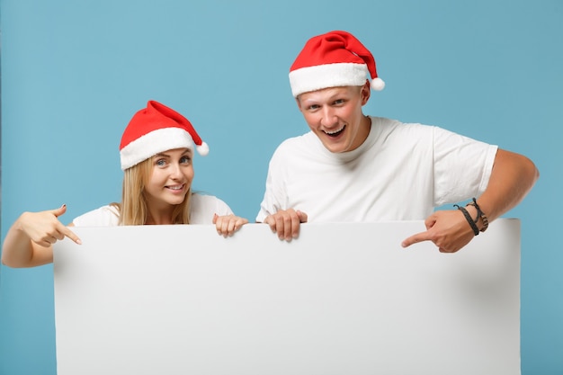 Sonriente joven pareja de santa amigos chico y mujer con sombrero de Navidad