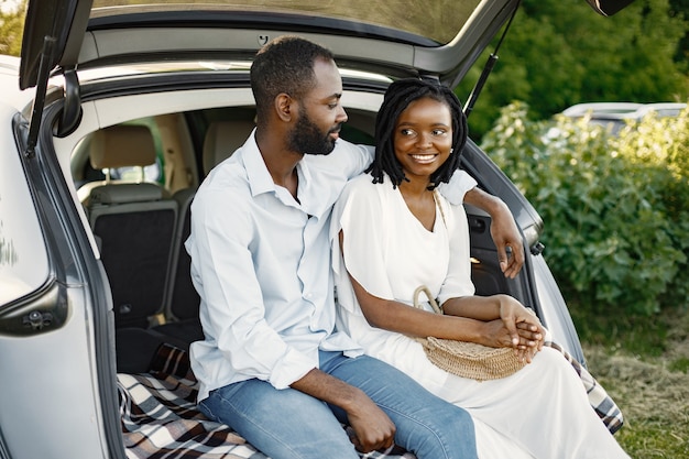 Sonriente joven pareja sentada en la parte trasera del coche. Etnia afroamericana. Amor, concepto de relación.