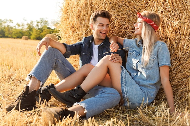 Sonriente joven pareja sentados juntos en un pajar