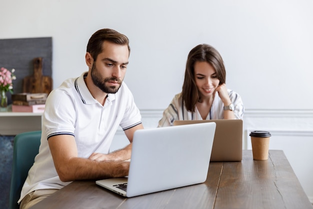 Sonriente joven pareja trabajando en un proyecto mientras está sentado en el escritorio en casa