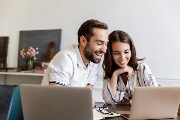 Sonriente joven pareja trabajando en un proyecto mientras está sentado en el escritorio en casa