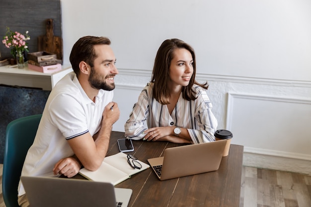 Sonriente joven pareja trabajando en un proyecto mientras está sentado en el escritorio en casa