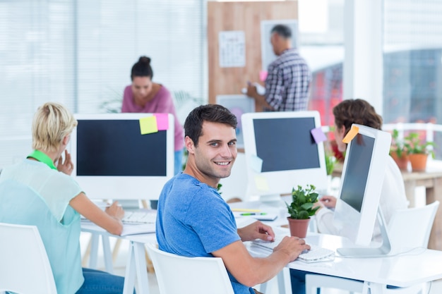 Sonriente joven que trabaja con su colega en el escritorio en la oficina