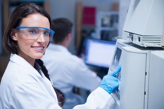 Foto sonriente joven químico usando la máquina