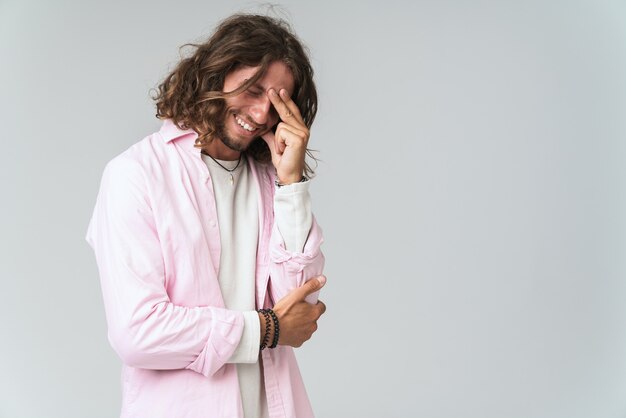 Sonriente joven relajado vestido con traje casual que se encuentran aisladas en gris