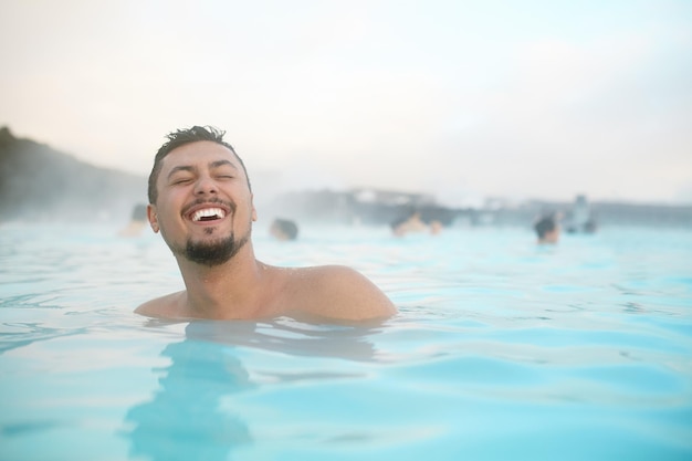 Sonriente joven relajándose en la piscina en Islandia