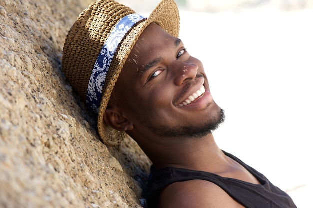 Sonriente joven con sombrero relajante al aire libre