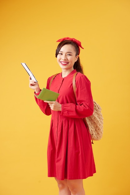 Sonriente joven turista con mochila con pasaporte y boletos de avión fondo de estudio amarillo
