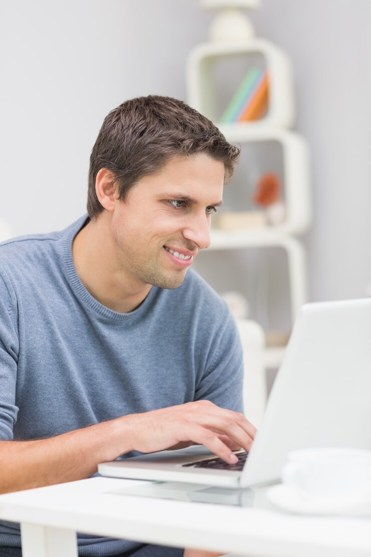 Foto sonriente joven usando la computadora portátil en la sala de estar