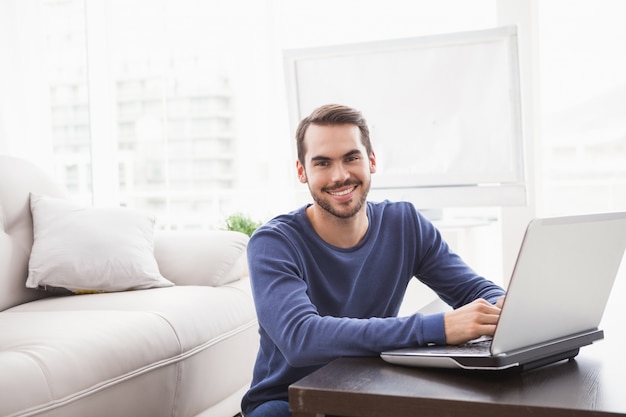 Sonriente joven usando su computadora portátil