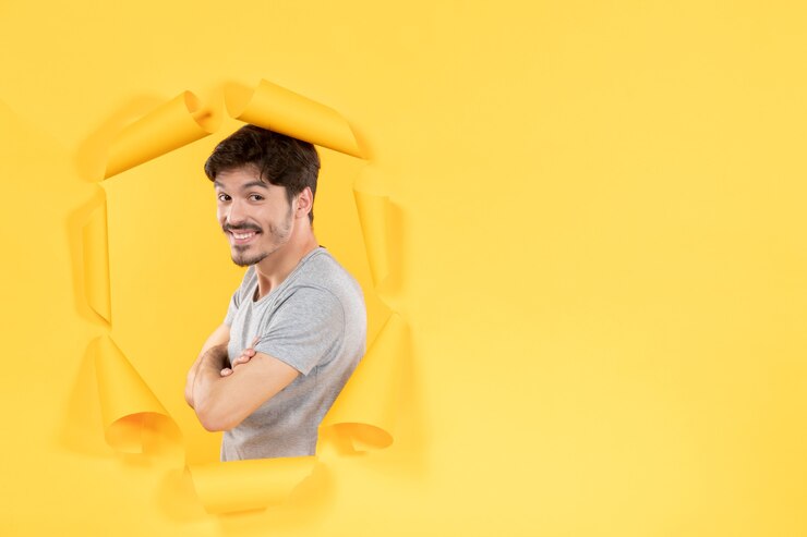 Sonriente joven varón sobre fondo de papel amarillo rasgado chico interior guapo facial