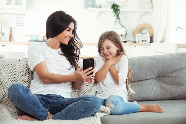 Sonriente madre e hija jugando con teléfono inteligente