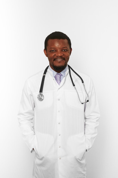 Sonriente médico barbudo negro hombre en bata blanca con estetoscopio aislado sobre fondo blanco.