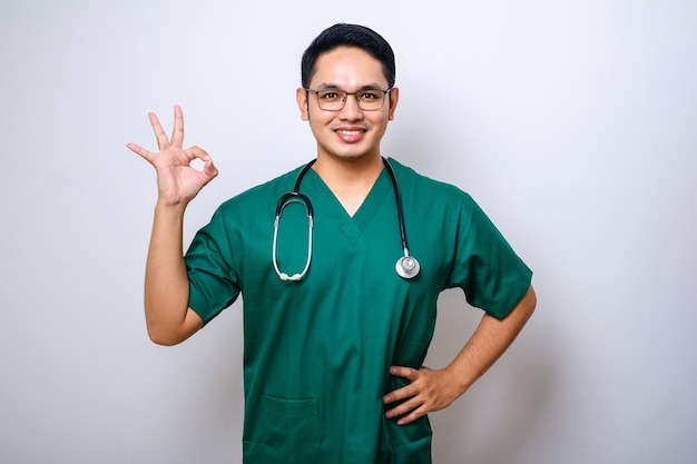 Sonriente médico masculino asiático enfermero que usa guantes de goma para asegurarse de que todo esté bien mostrando un gesto correcto